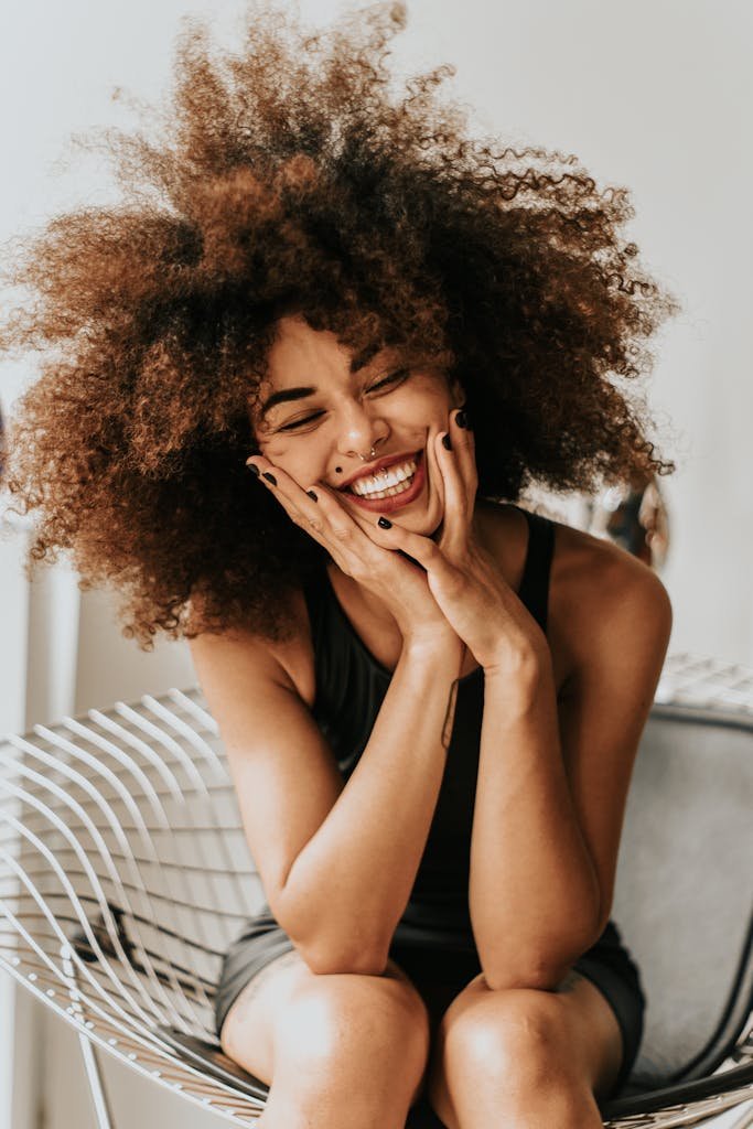 13 vertus du thé vert matcha 4 A cheerful woman with an afro hairstyle sitting indoors, showcasing happiness and style.