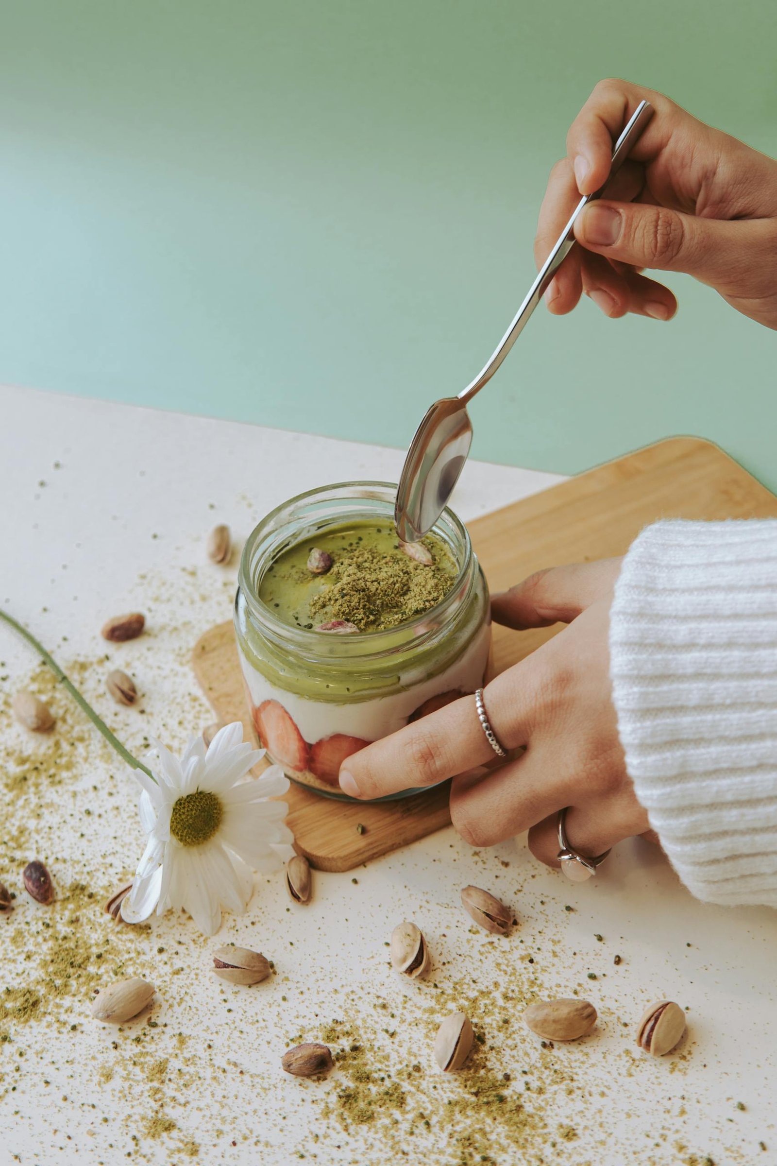 Delicious creamy matcha dessert in a jar topped with pistachios, perfect for a sweet snack.