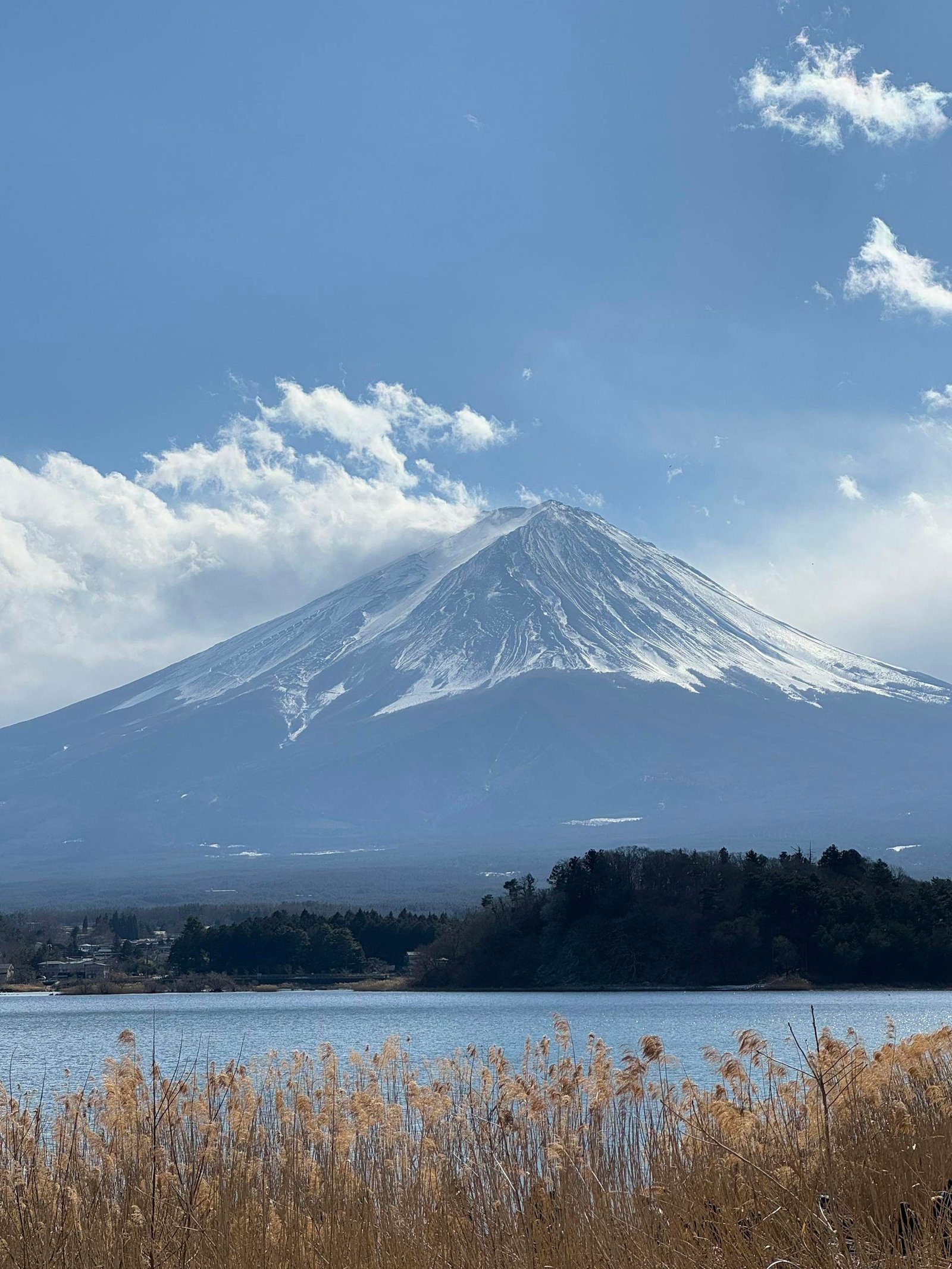 Stunning winter view of snow-capped Mount Fuji across the lake under a bright sky.