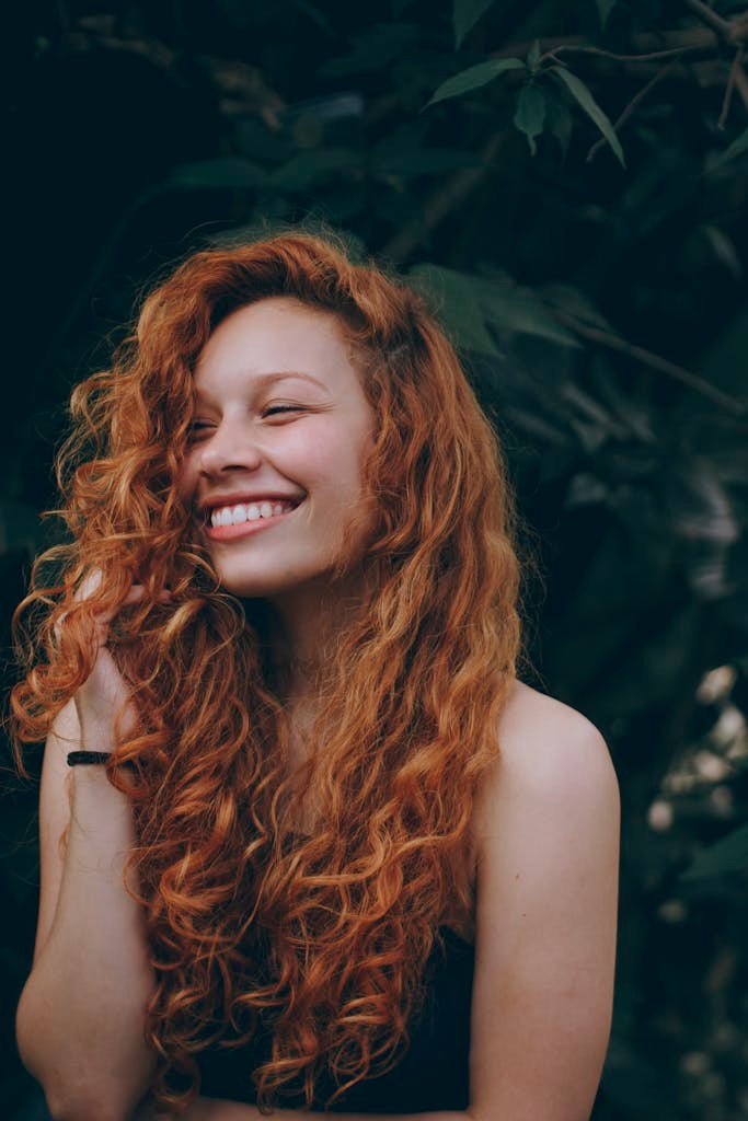 Thé matcha bienfaits cheveux : cela rend-il les cheveux plus longs? 3 A candid portrait of a joyful woman with curly red hair, expressing natural beauty and happiness.