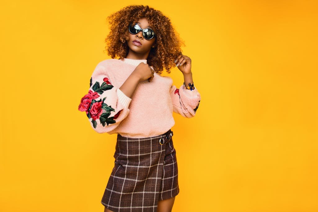 Thé matcha bienfaits cheveux : cela rend-il les cheveux plus longs? 4 Chic woman with afro hair in a floral sweater and plaid skirt posing confidently.