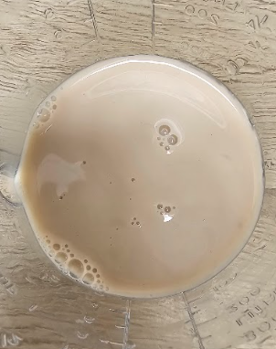 Couleur beige du lait de noisette Alpro versé dans un verre